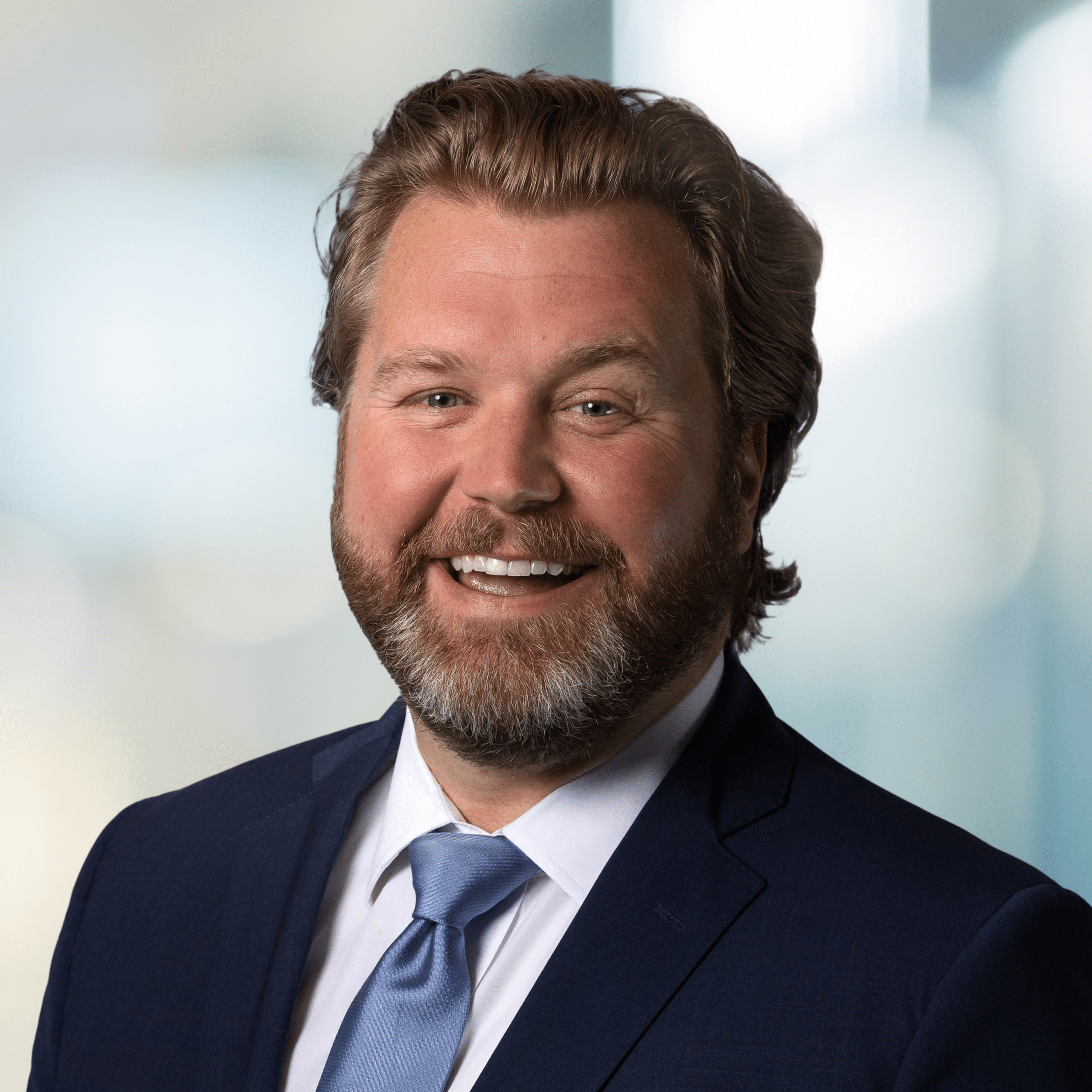 A smiling headshot of Gordon Wadley, COO, Dream Office REIT, wearing a black suit and blue tie