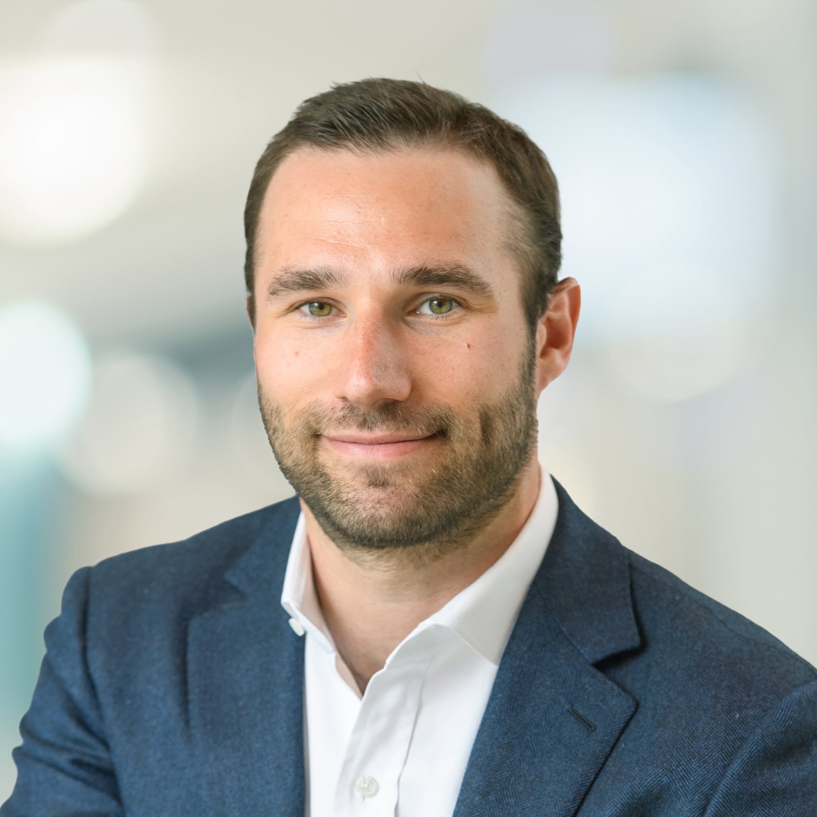 A smiling headshot of Jamie Cooper, President, Development & Income Properties & Portfolio Manager, Dream Impact Fund, wearing a blue blazer and white button up shirt
