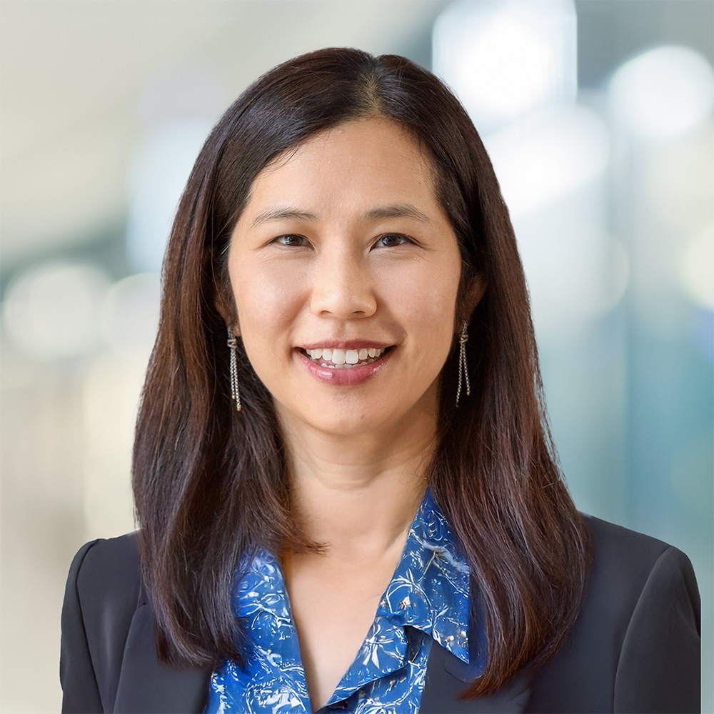 Smiling headshot of Lenis Quan, CFO Dream Industrial Reit, wearing a black blazer, blue shirt and earrings