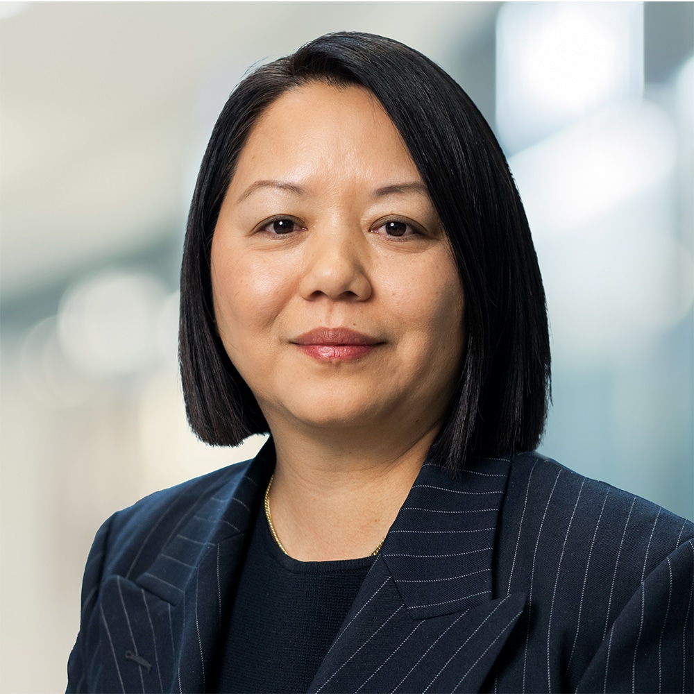 Smiling headshot of Tsering Yangki, EVP, Real Estate Finance & Development, wearing a striped blazer