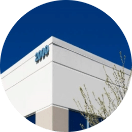a close up of the top corner of an industrial building that is surrounded by a deep blue sky, the shite building has the numbers 2000 written in a soft blue tone
