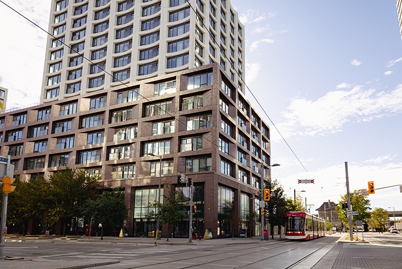 Canary House, a residential and retail building with modern finishes, a red street car is parked outside