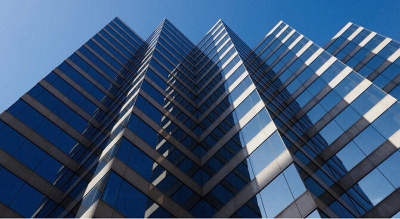 a tall building with glass windows against a bright blue sky.