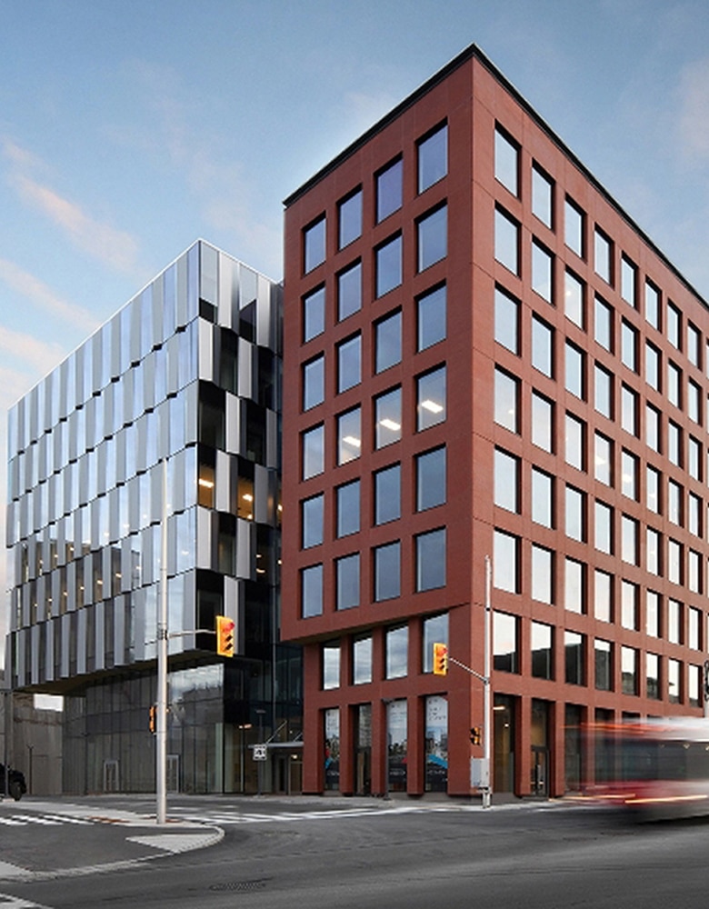 A red brick building with windows on the side of the street stands tall next to an empty manicured street