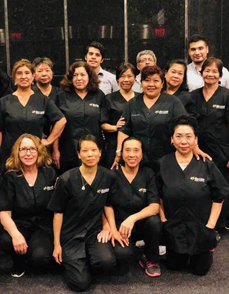 Bee-clean staff poses for a photo in front of a black wall in their traditional black uniforms.
