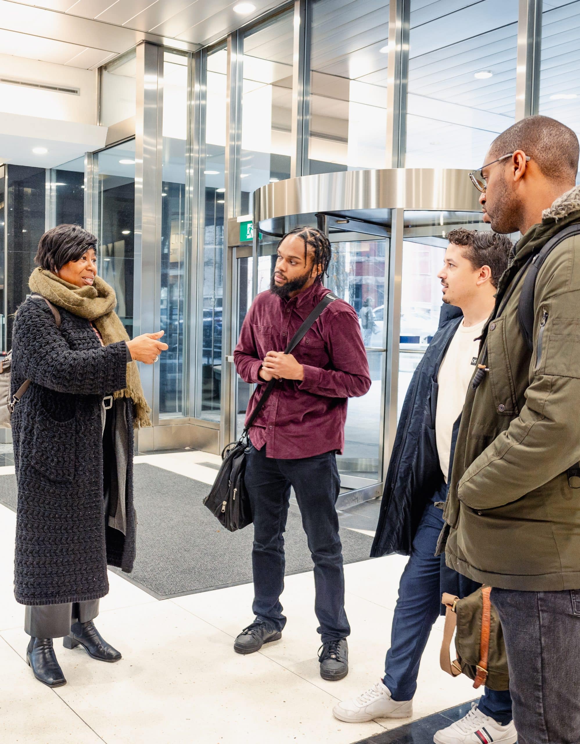 Four people standing in a semi circle having a meeting in a lobby of an office building