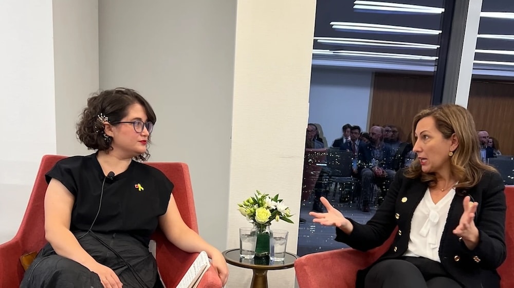 Ana Bailo, and host chat on Affordable Housing Strategies on Camera, sitting in red chairs