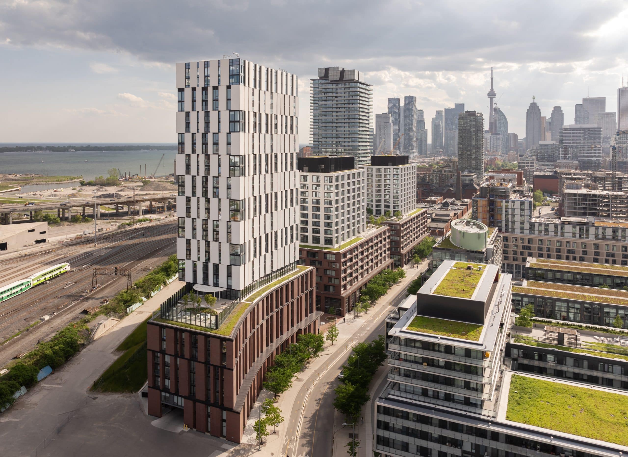 Bird’s-eye view of Maple House condos in Toronto, showcasing a cluster of modern mid-rise and high-rise residential buildings with sleek glass façades; surrounded by landscaped green spaces, pedestrian pathways, and nearby urban amenities