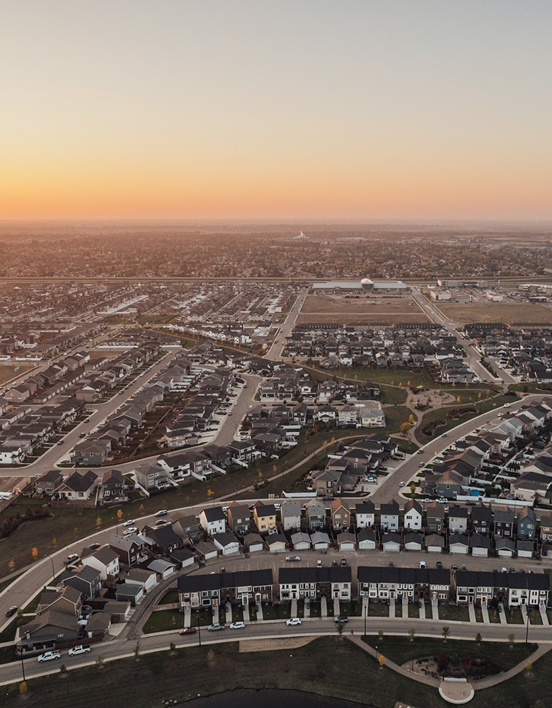 Brighton Community suburban landscape at sunset, featuring paved city roads and neatly arranged houses bathed in warm golden light