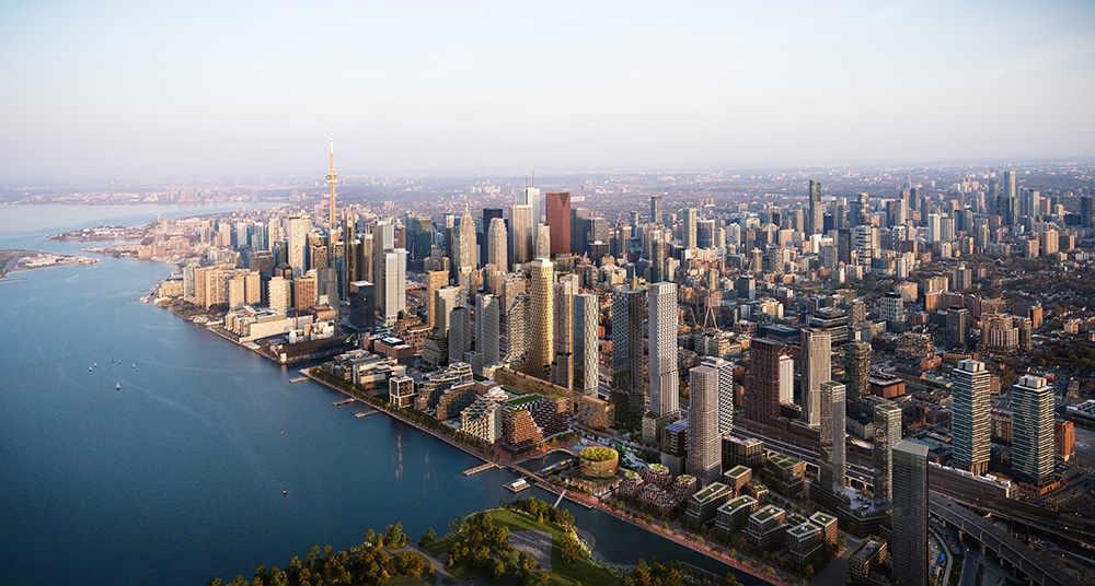 Quayside Community, A beautiful sunset over a calm blue, lake Ontario, with delicate orange and pink hues reflecting on the water hugged by a well developed city shore line with the CN Tower peeking in the background