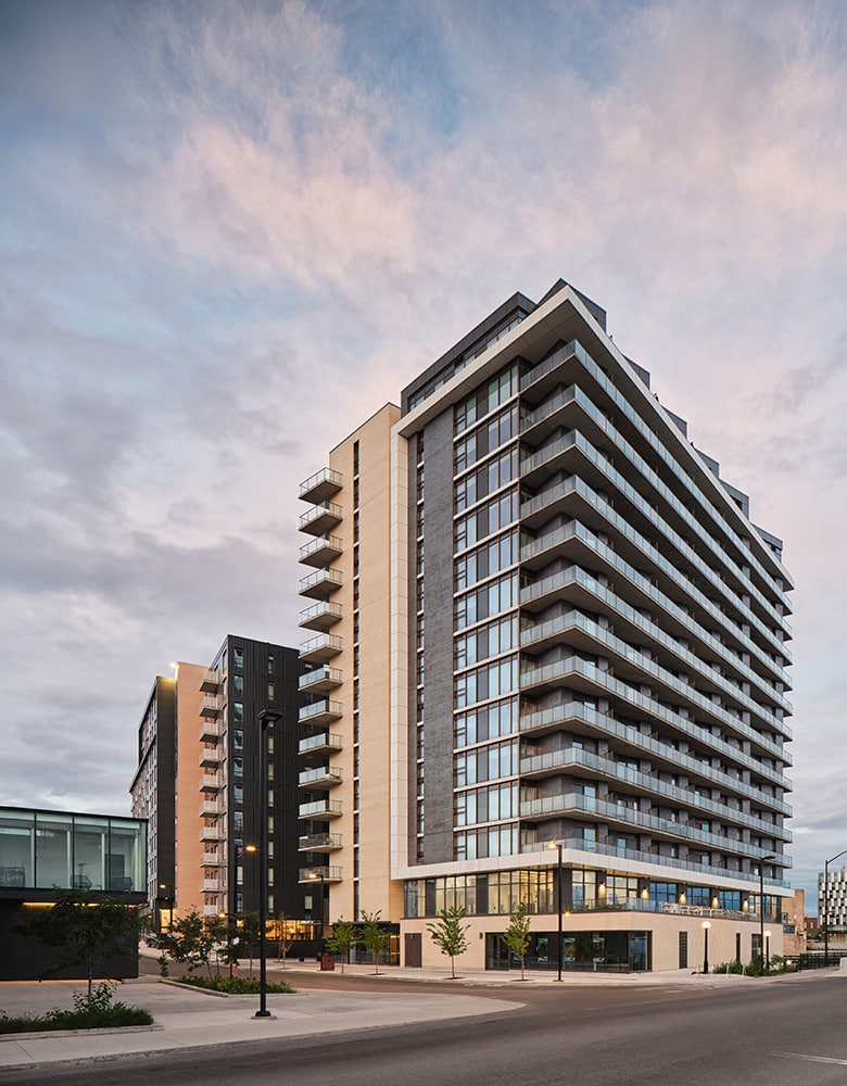 Aalto Suites, in Zibi Gatineau Quebec, a tall residential building with wrap around balconies on paved city sidewalks